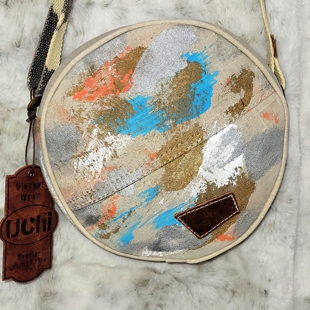 Canvas round crossbody purse. Has splashes of color.